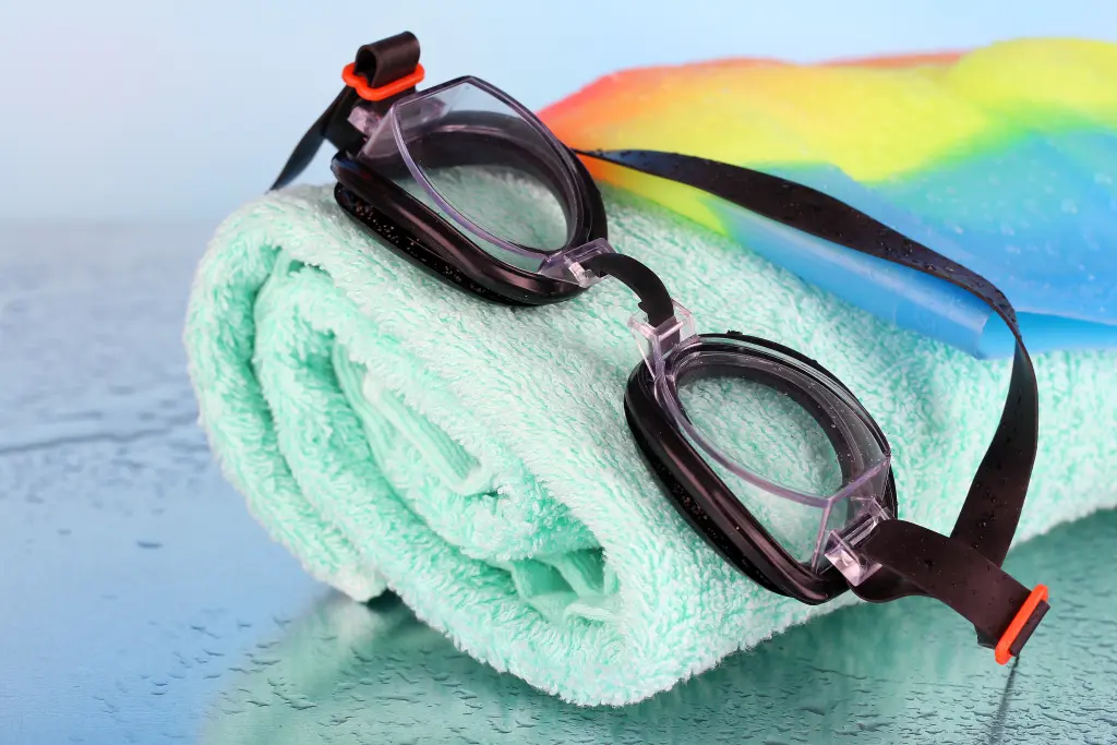 set-for-pool-swim-cap-goggles-and-towel-on-blue-background.jpg